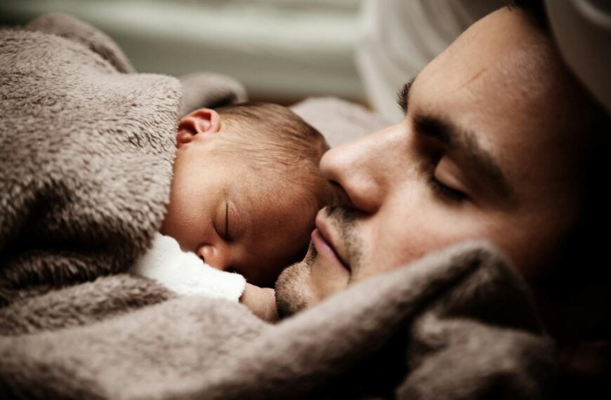 A touching close-up of a father and his baby peacefully napping together.