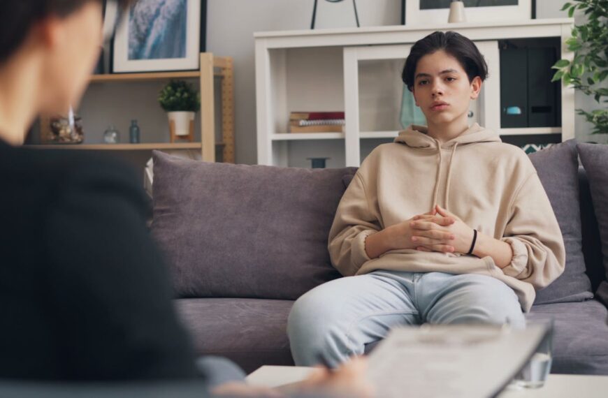Calm teenager sitting on a sofa during a therapy session with a professional therapist.