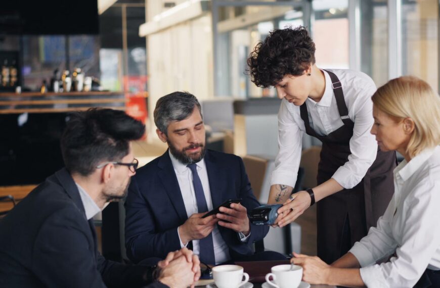 Business professionals in a cafe settling payment with a waiter.