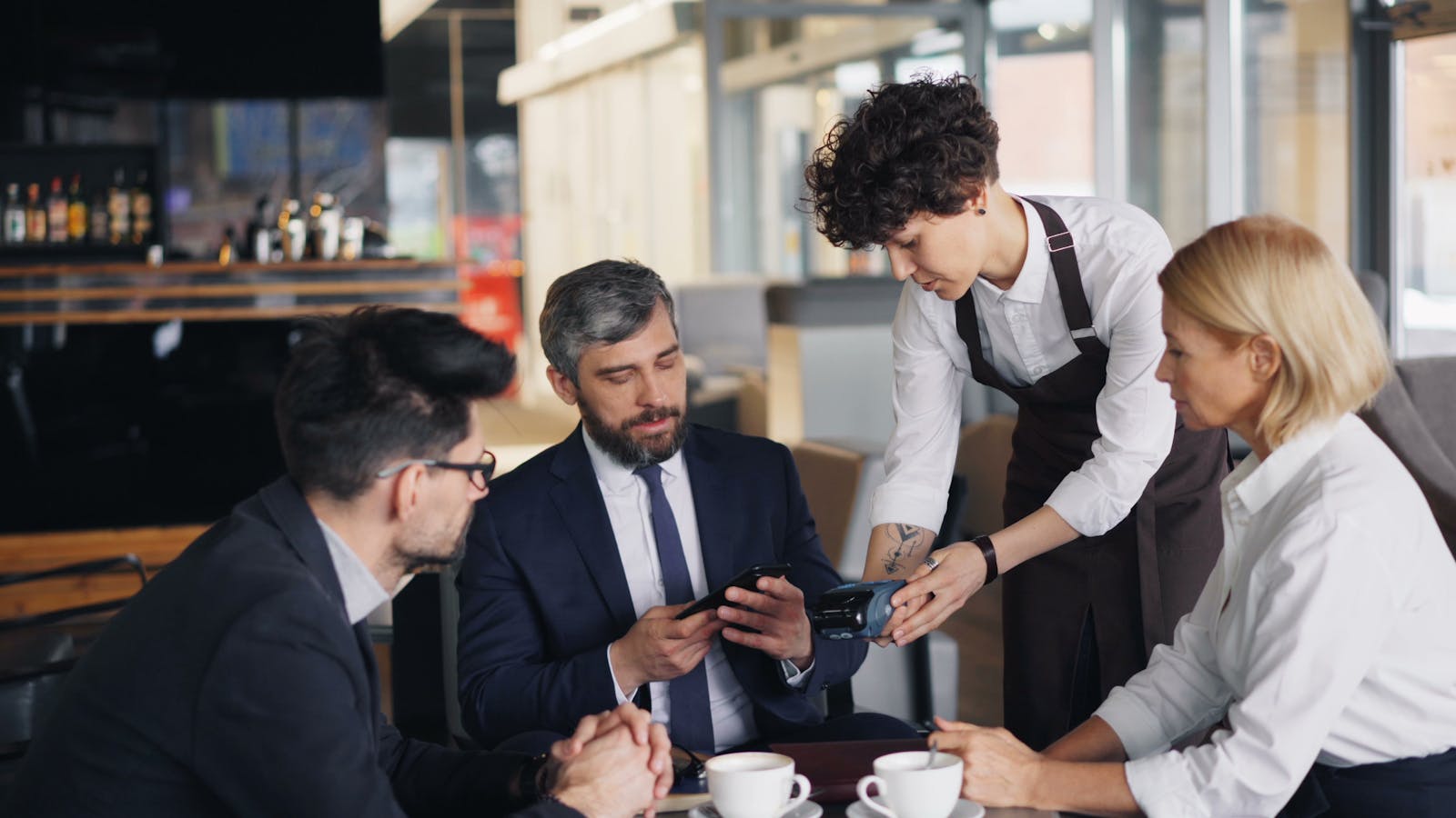 Business professionals in a cafe settling payment with a waiter.