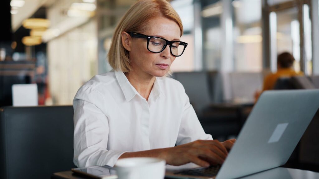 Focused woman using laptop in a café, epitomizing modern entrepreneurship.