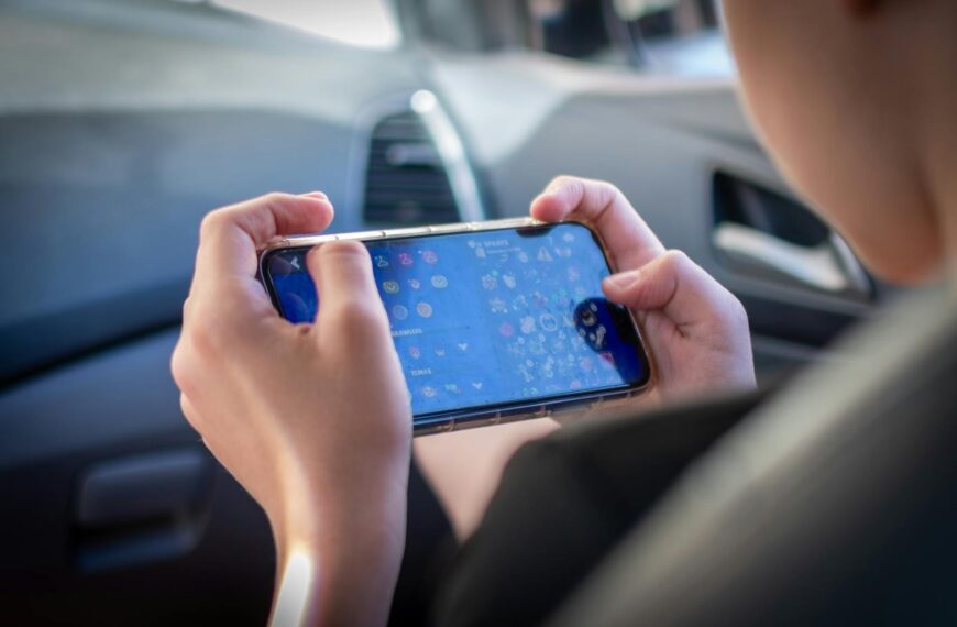 A teenager plays a mobile game while sitting inside a car, showcasing modern technology engagement.