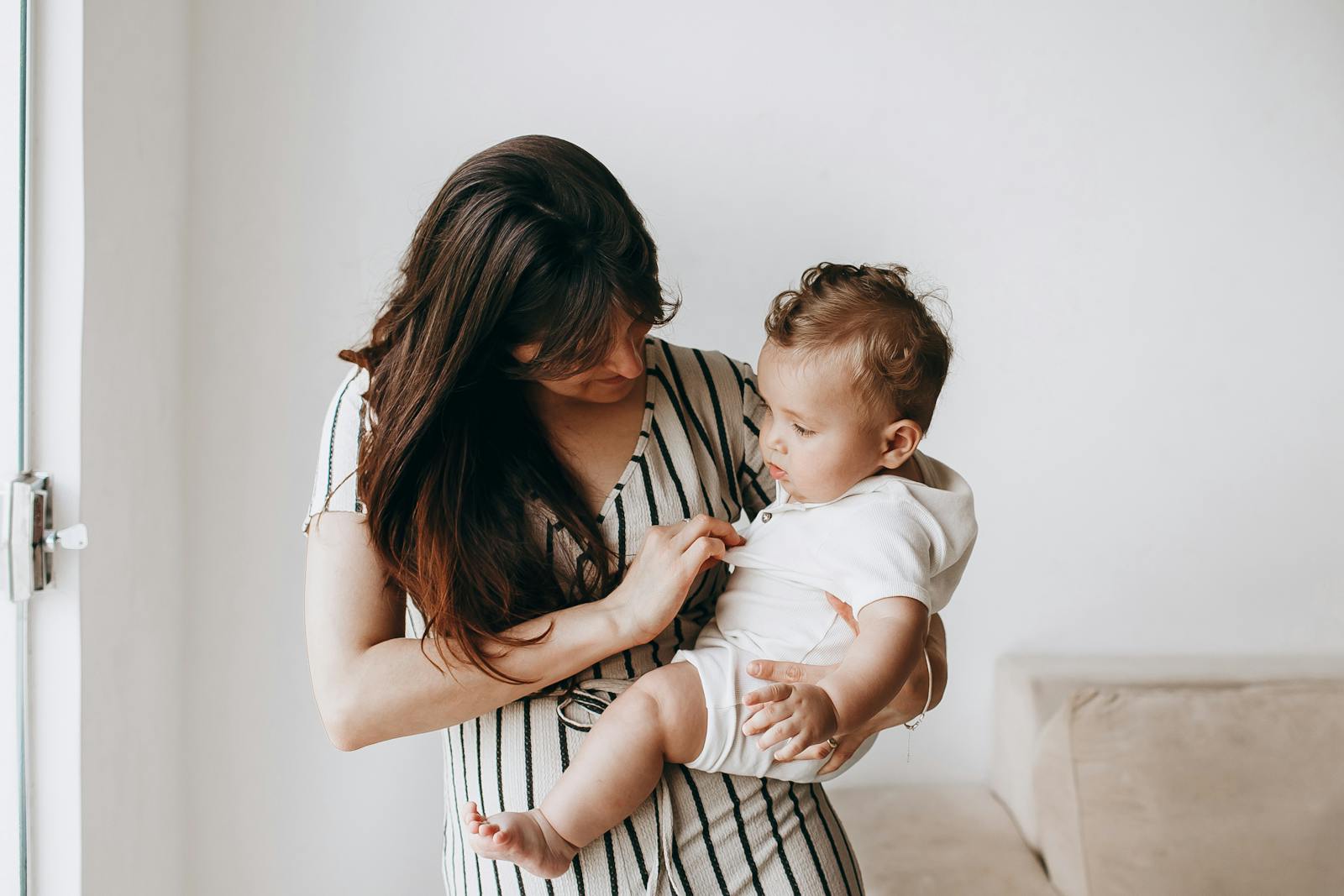 A tender moment between a mother and her baby indoors, showcasing love and care.