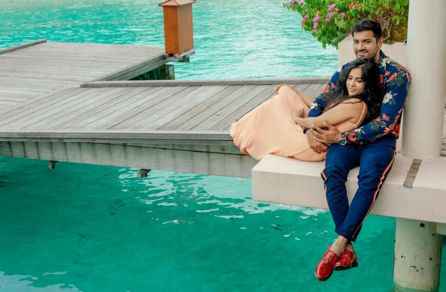 Couple embracing by a serene Maldives pier, capturing romance and tropical getaway vibes.