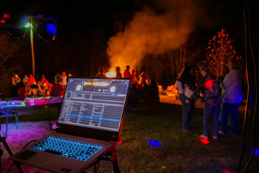 Vibrant outdoor night party scene featuring a DJ setup and blazing bonfire in West Virginia.