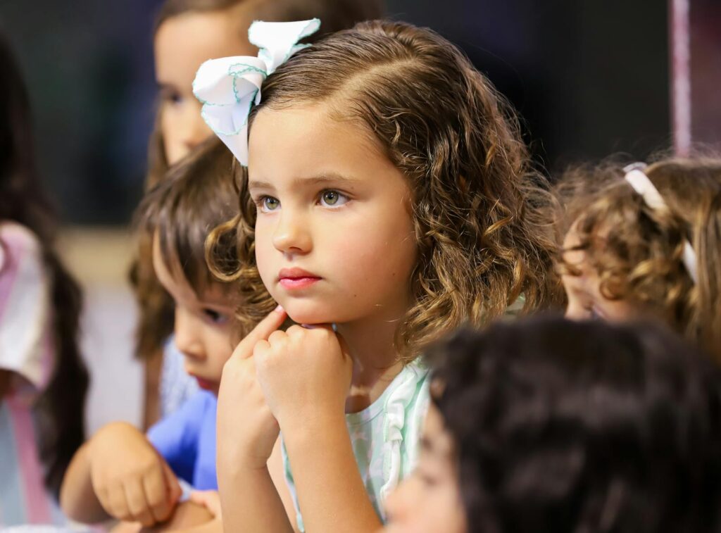 Group of children attentively listening, showcasing curiosity and focus during an event.