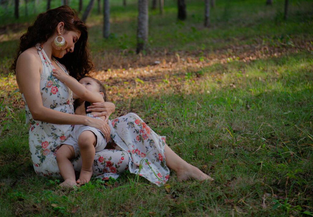 A mother lovingly breastfeeding her child in a peaceful outdoor setting.