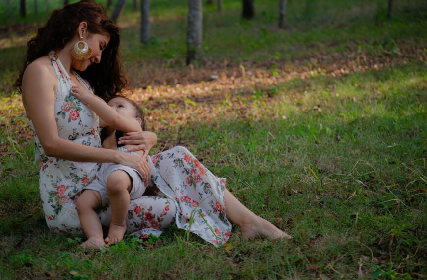 A mother lovingly breastfeeding her child in a peaceful outdoor setting.