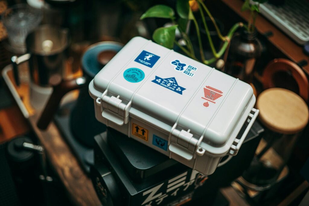 White coffee gear case with colorful stickers, surrounded by barista tools, blending modern coffee culture.