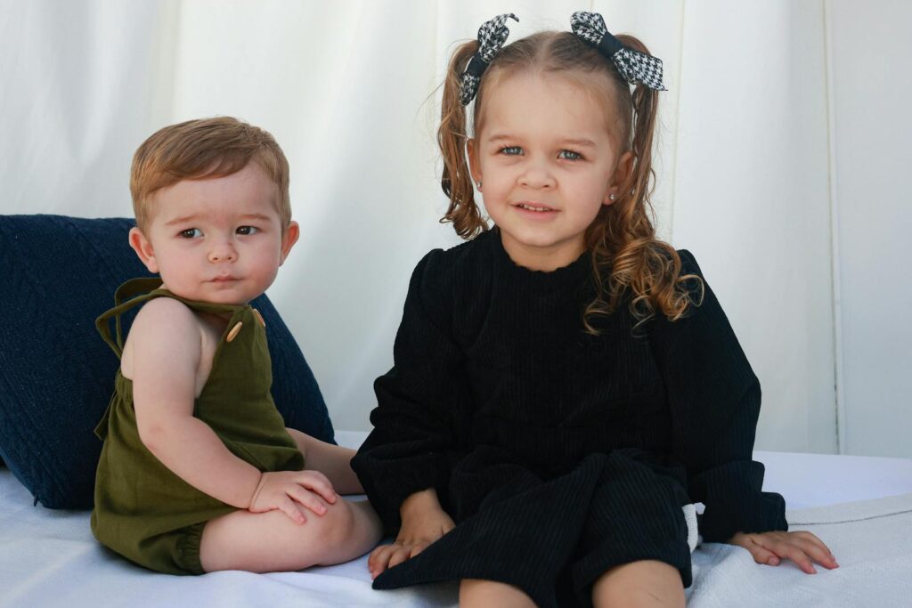 Cute siblings sitting indoors, capturing a heartwarming moment.