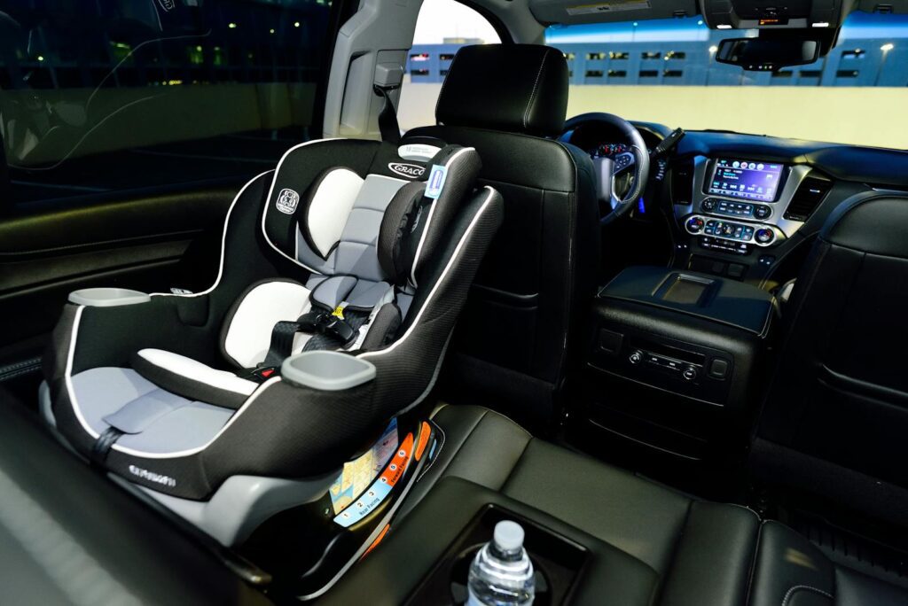 Interior of a car featuring a child safety seat and illuminated dashboard, captured at night.