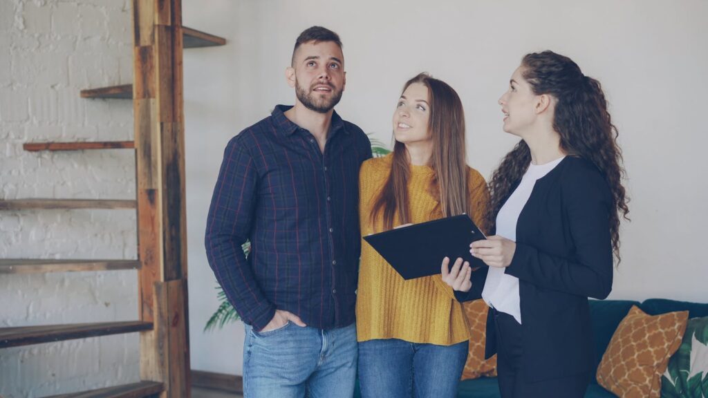 Young couple exploring a new home with their real estate agent, discussing options and features.