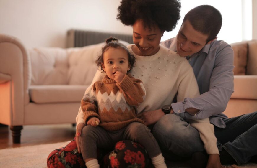 A joyful family moment with parents and child sitting on the floor in a cozy living room.