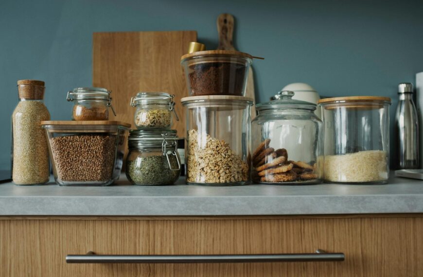Glass jars with pantry essentials like oats, cookies, and spices on a kitchen counter.