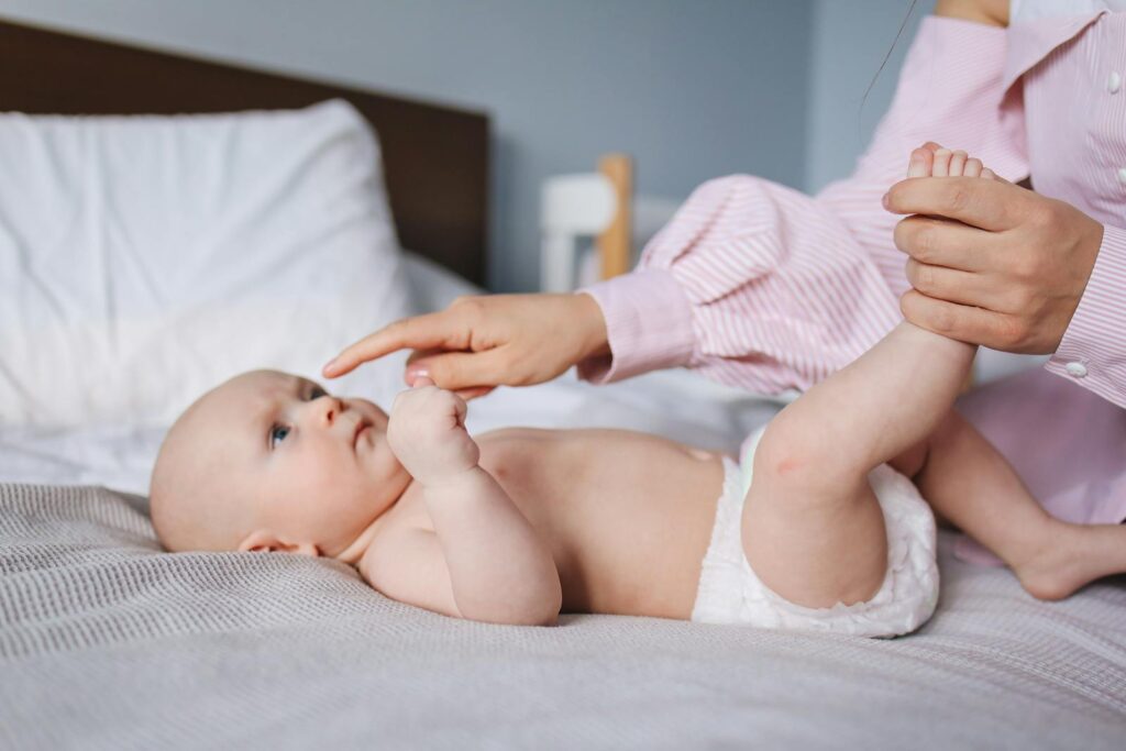 A mother tenderly plays with her baby on a bed, showcasing warmth and affection.