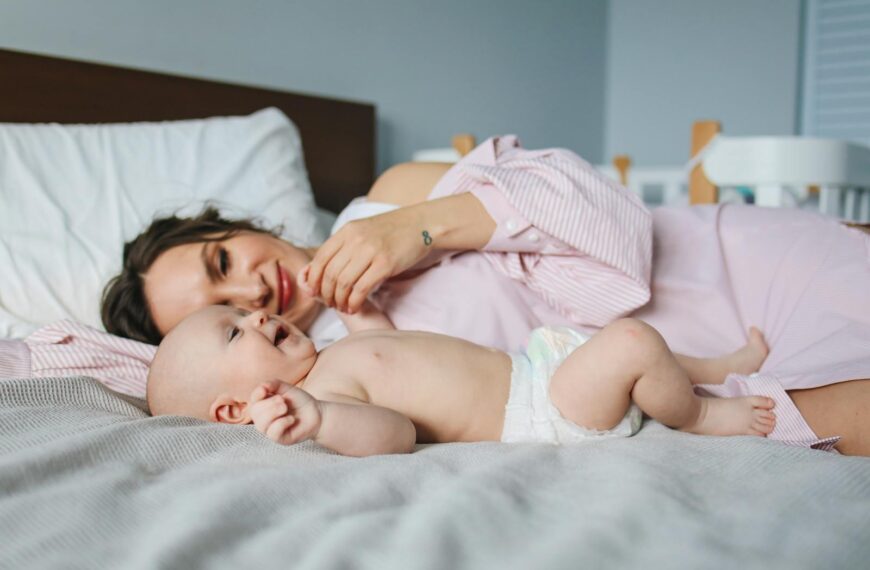 A mother and her baby lying on a bed, showcasing a bond of love and warmth indoors.