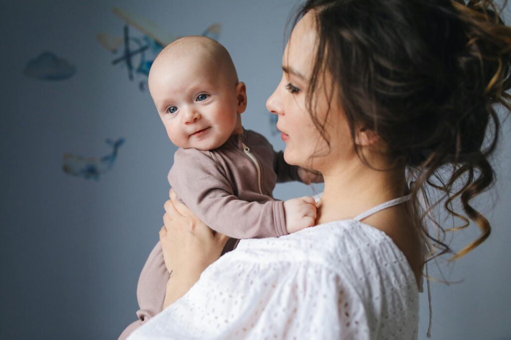 A mother joyfully holds her baby in a cozy indoor setting, highlighting family love and affection.