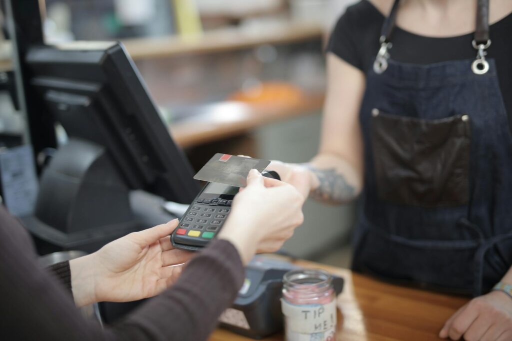 Close-up of customer and cashier during a credit card transaction at a store counter indoors.