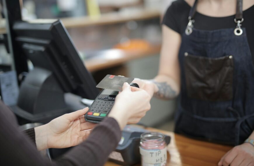 Close-up of customer and cashier during a credit card transaction at a store counter indoors.