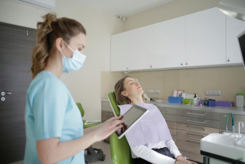 A female dentist using a tablet while attending to a patient in a modern dental clinic.