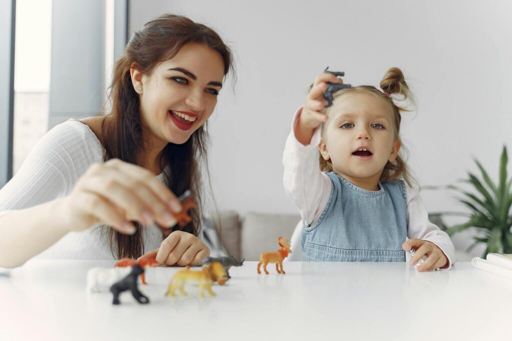 A joyful moment of a mother and daughter playing with toy animals indoors.