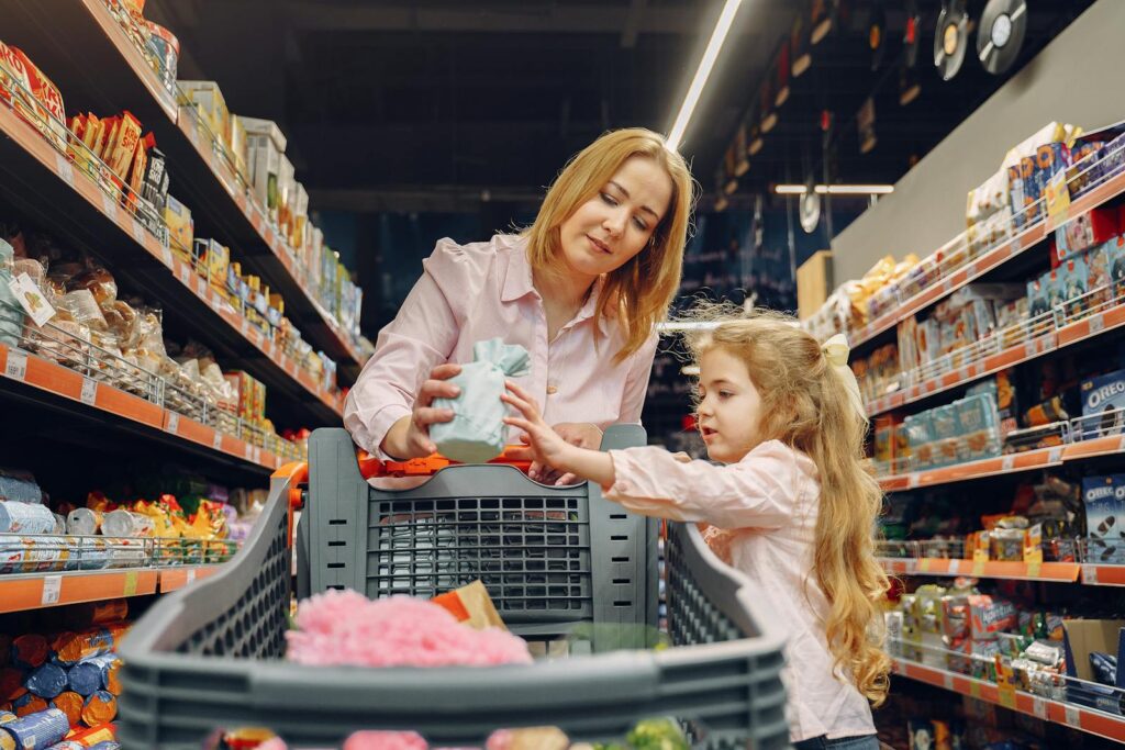 A mother and daughter shopping together in a supermarket aisle, enjoying quality time.