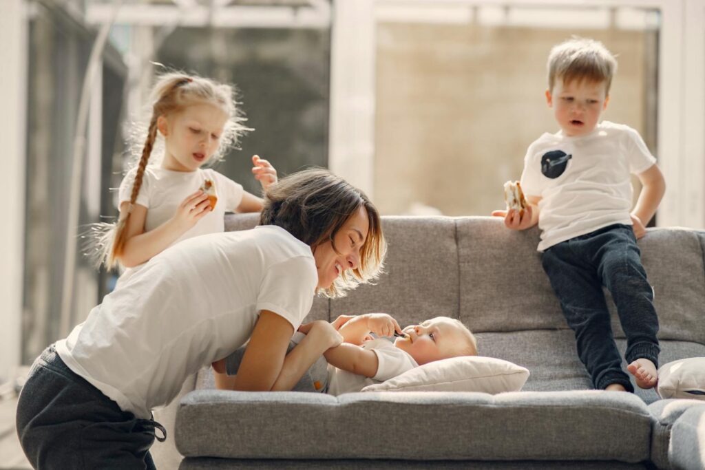 Mom playing with her children on the couch, enjoying a cheerful and loving family moment.