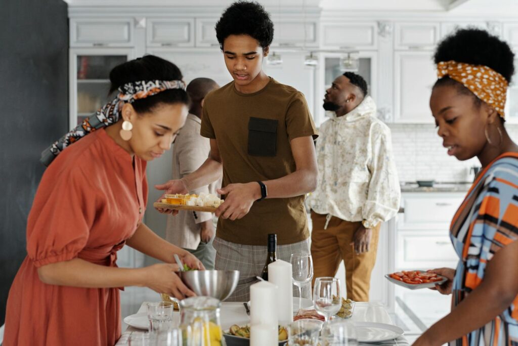 A family enjoys a gathering in a stylish kitchen, sharing food and togetherness.