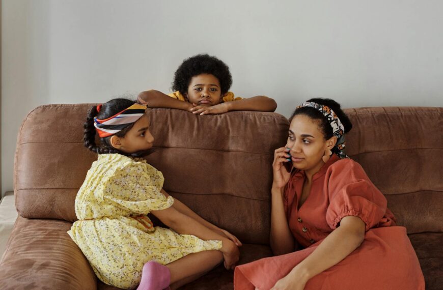 Mother and children sitting on a couch at home. Relaxed family moment indoors.