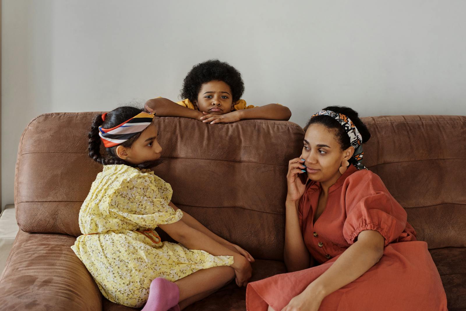 Mother and children sitting on a couch at home. Relaxed family moment indoors.
