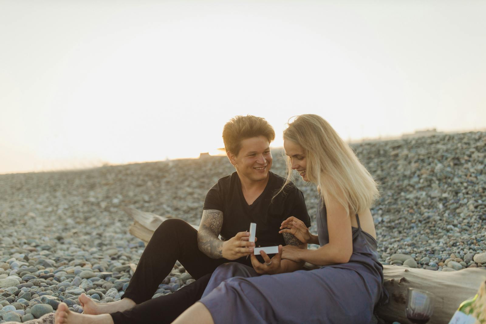 A couple experiencing a romantic proposal on the beach at sunset, capturing love and surprise.
