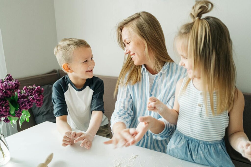 A mother and her two children enjoy a fun baking session inside their home.
