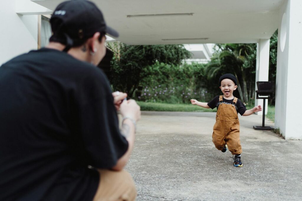 Father capturing a joyful moment as son runs happily in the garden.