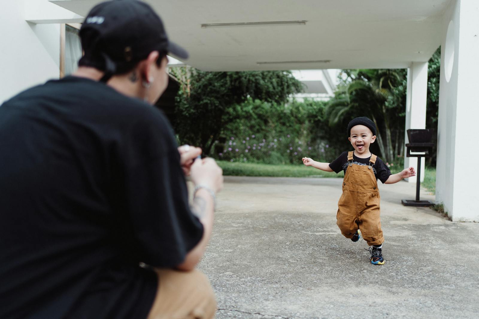 Father capturing a joyful moment as son runs happily in the garden.