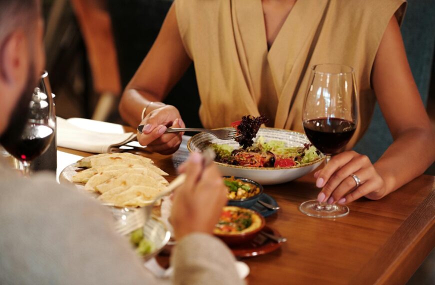 Couple enjoying a romantic dinner with wine and delicious meals at a cozy restaurant.