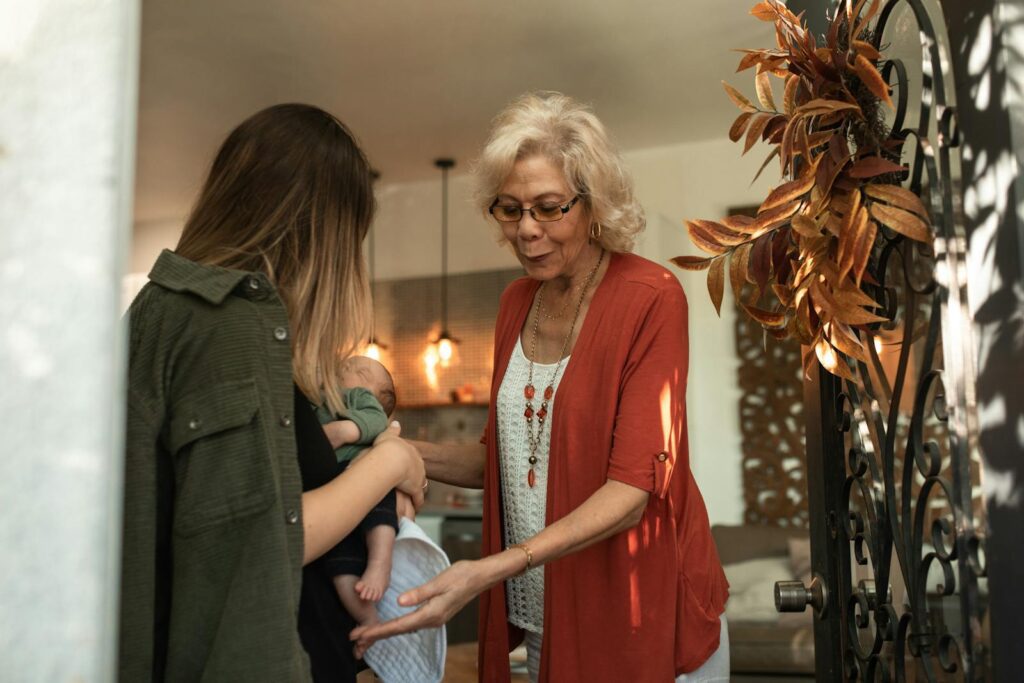 A tender moment of a grandmother greeting a family with a newborn baby during a holiday gathering.