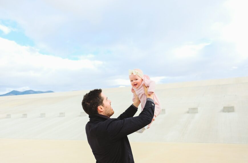 man carrying baby during daytime