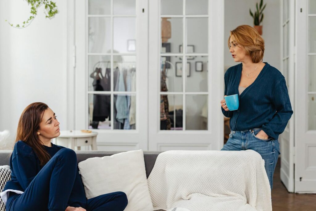 Two women in a cozy home setting having a casual conversation over coffee.