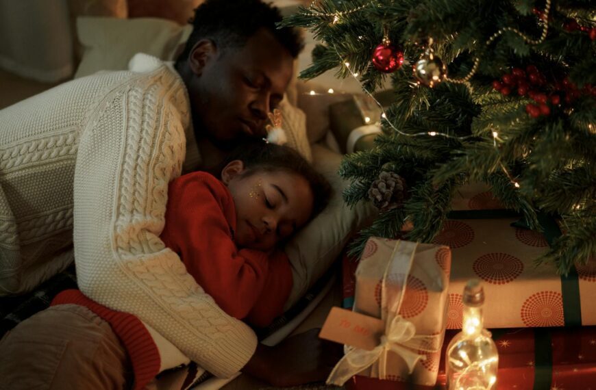 Peaceful moment between a father and daughter sleeping by the Christmas tree.