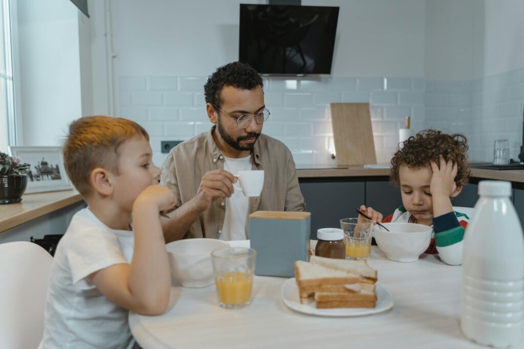 A father and his two young sons sharing a breakfast moment at home.