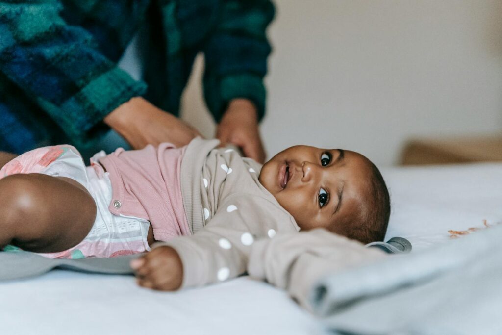 Cute baby in diaper on a bed, receiving care. Perfect for childcare themes.