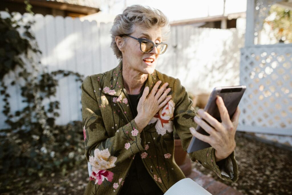 Senior woman engaging in a video call outdoors with a smartphone, expressing joy and communication.
