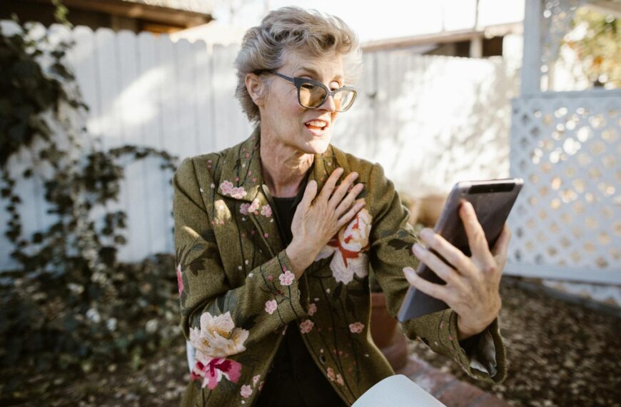 Senior woman engaging in a video call outdoors with a smartphone, expressing joy and communication.