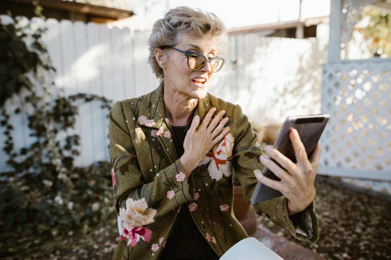 Senior woman engaging in a video call outdoors with a smartphone, expressing joy and communication.
