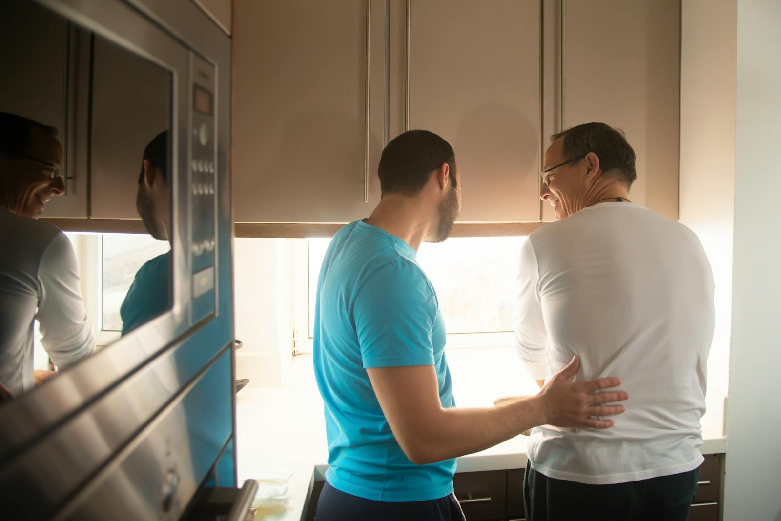 Two men enjoy cooking together in a bright kitchen, reflecting love and togetherness.