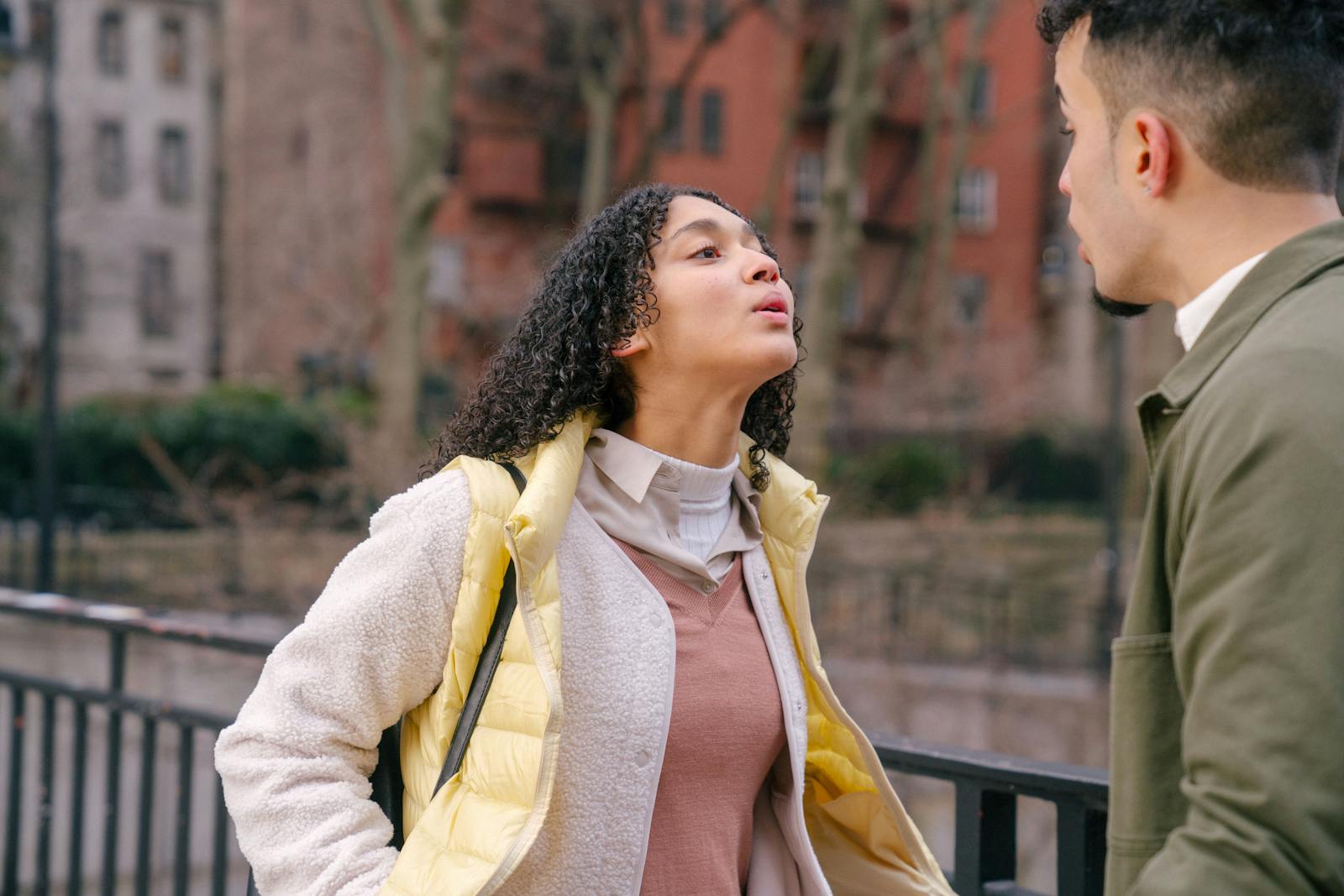 A young couple having an intense conversation outdoors, showcasing a moment of conflict.