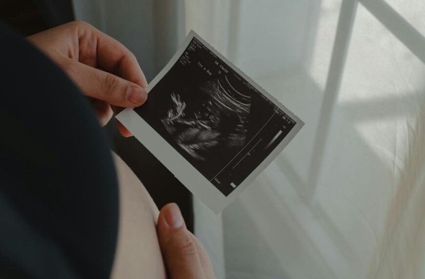 Pregnant woman holding an ultrasound scan of her unborn child, symbolizing motherhood.