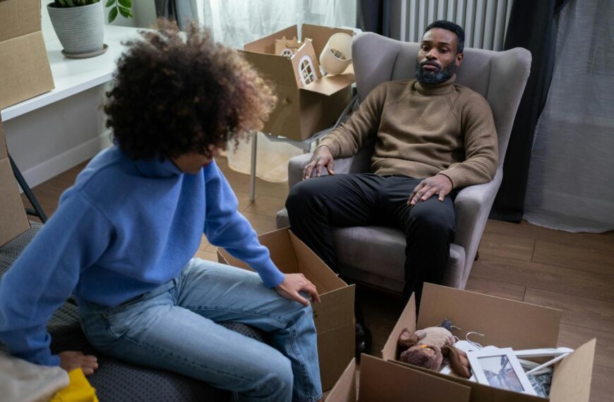 A couple in a cozy living room packing boxes during a move.