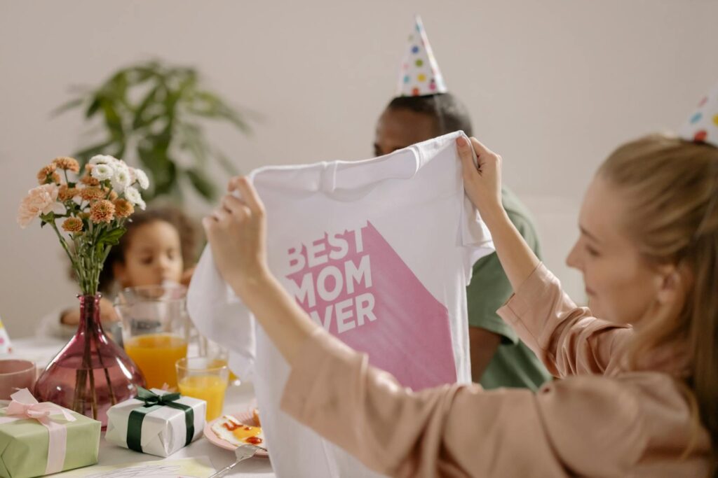 A joyful indoor Mother's Day celebration featuring a family with a 'Best Mom Ever' shirt.