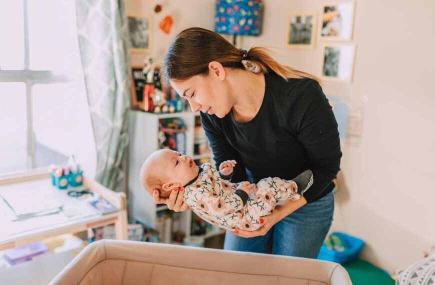 A mother lovingly holds her newborn baby in a cozy nursery, symbolizing motherhood and togetherness.